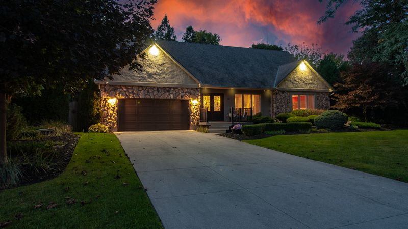 Twilight exterior photo of a stone bungalow with glowing windows